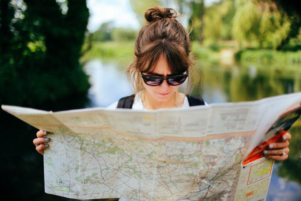 Mujer sosteniendo un amplio mapa de papel. En su lugar hay algunas apps que para tu próximo viaje que puedes descargar para tener mapas digitales